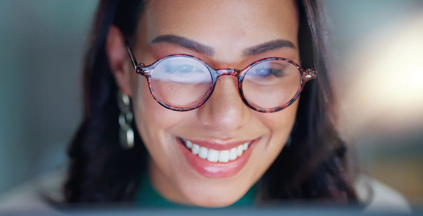 Une gestionnaire souriante lit son écran, le visage éclairé par la lumière de l’interface